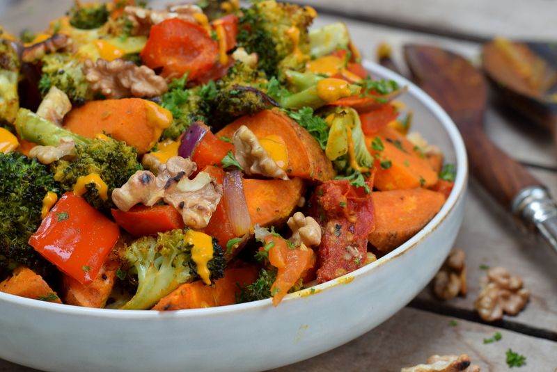 Zijaanzicht een witte kom met geroosterde salade met zoete aardappel en een kurkumasausje