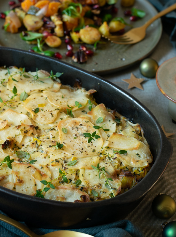 Zijaanzicht: ovenschotel met aardappel-preigratin op de achtergrond geroosterde wintergroenten
