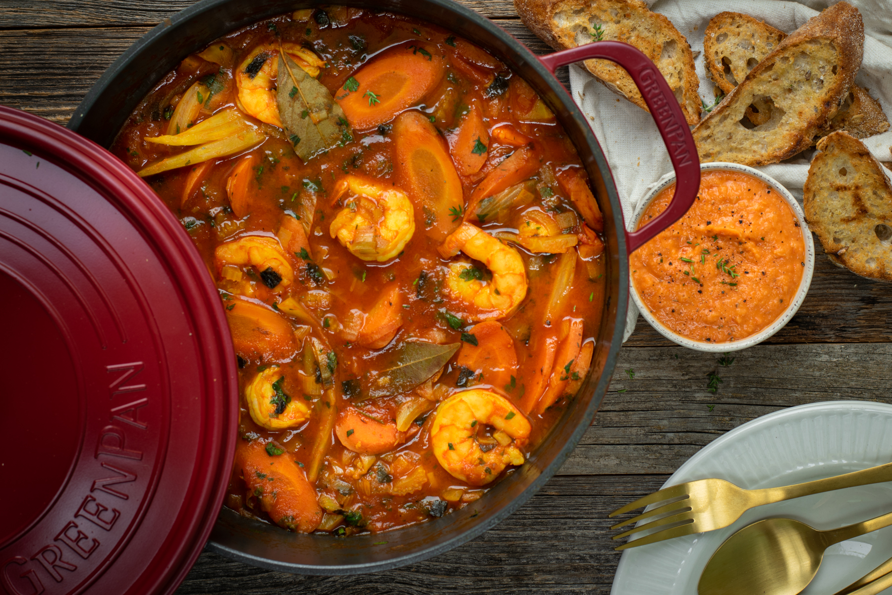 Bovenaanzicht van een bordeaux stoofpot gevuld met bouillabaise met scampi's.