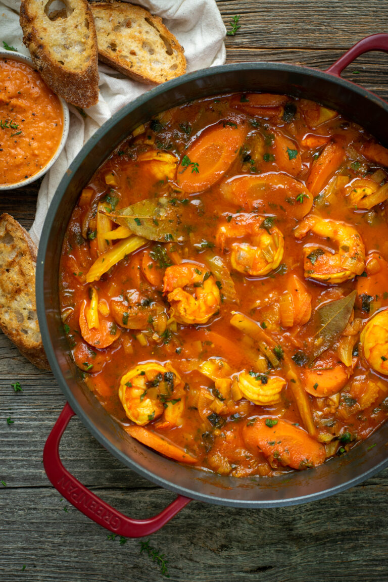 Bovenaanzicht van een bordeaux stoofpot gevuld met bouillabaise met scampi's.